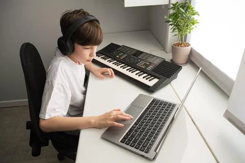 Boy learning music online using laptop and keyboard Stock Photos