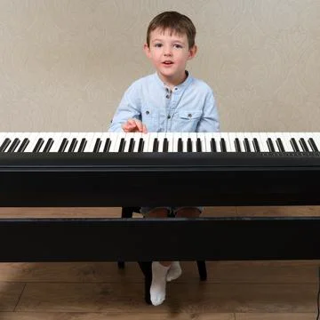 Boy learning to play on a black digital piano. Music education for children.. Stock Photos