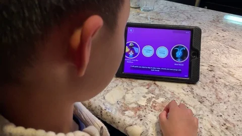 Boy learning to play piano on the iPad using an iTunes app called "Simply Stock Footage 108842296