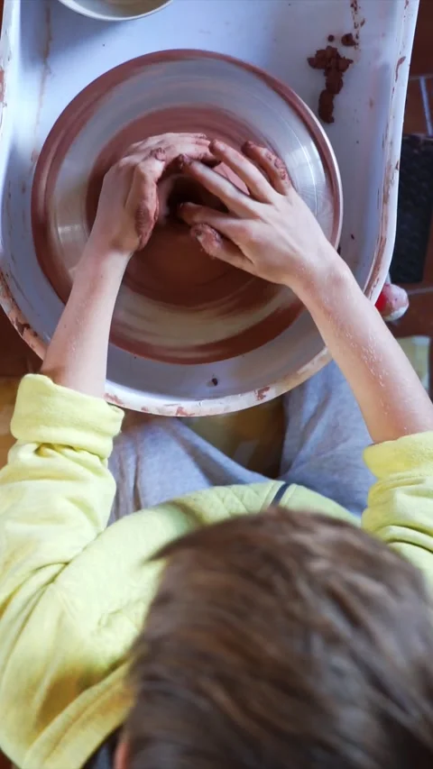 Boy learning potter's wheel seen from above Stock Footage 258828973