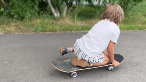 Boy learning to ride a skateboard on the road Stock Footage 247448087