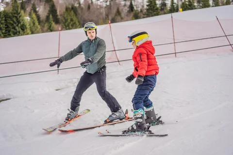 Boy learning to ski, training and listening to his ski instructor on the slope Stock Photos