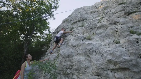 The boy learns to climb rocks with an instructor Stock Footage 94346820