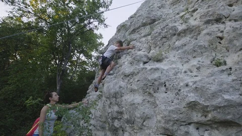 The boy learns to climb rocks with an instructor Stock Footage 94346838