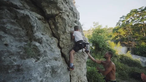 The boy learns to climb rocks with an instructor Stock Footage 94346874