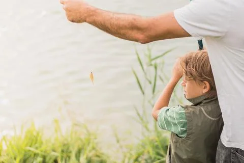 A boy learns how to fish under the guidance of an adult Stock Photos
