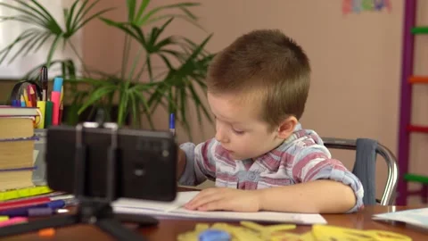 Boy learns remotely by smartphone.Little boy sits at the table. Distance Stock Footage 162187041