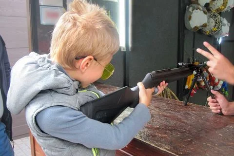 Boy learns to shoot at shooting range under guidance of an instructor Stock Photos