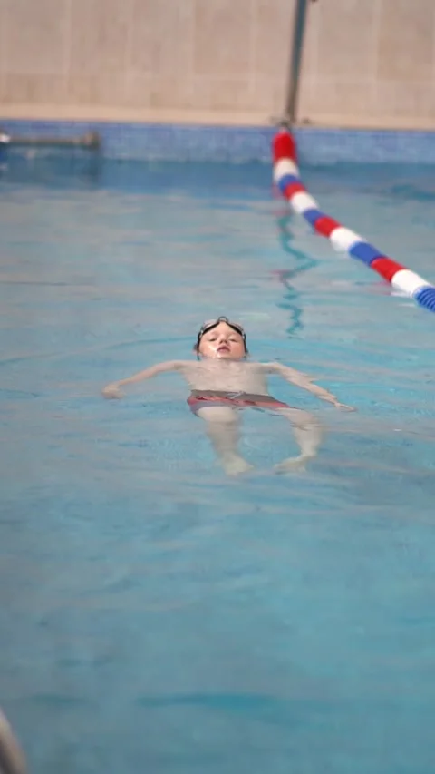 Boy learns to swim on his back Stock Footage 310141223