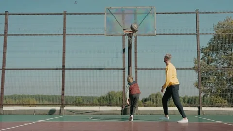 Boy learns to throw basketball ball with father on a court on a sunny day Video stock 166833855