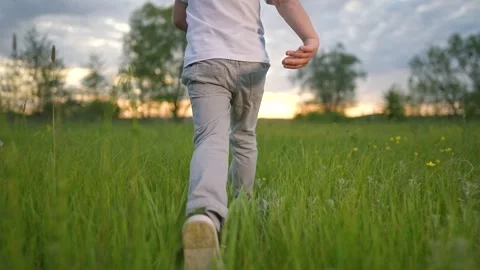 Boy legs move fast across summer field. Nature light surrounds motion. Grass Stock-Footage 318445376