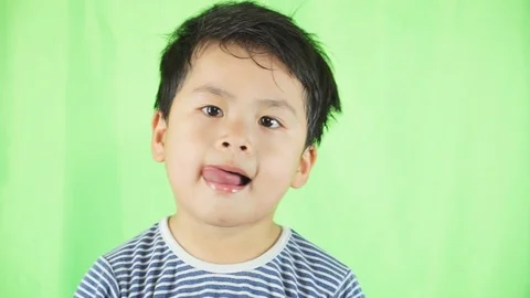 The boy licks his lips, chewing the boy's mouth on green background, 스톡 동영상 88623948
