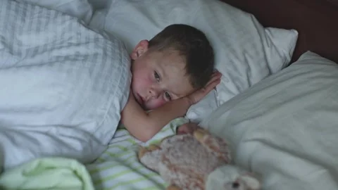 Boy lies on bed snuggling stuffed toy slowly falling asleep gentle comforting Stock-Footage 295003010