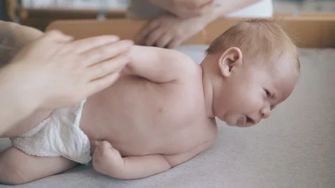 Boy lies on changing table and nurse practices arm massage Stock Footage 113462390