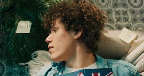 A boy lies on the couch and learns a foreign language. Cards with words are Stockbeeldmateriaal 218236790