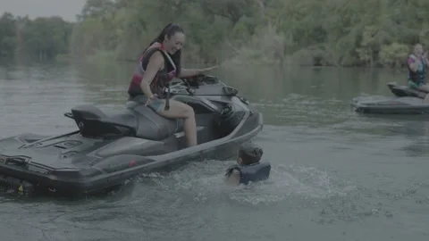 Boy in life jacket jumps into the water off of jetski Stock Footage 323466339