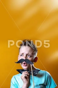 Boy in a light t-shirt with a mustache and a bow sings and says funny Stock Photos