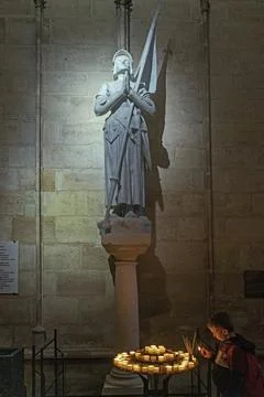 Boy lights candle below statue of Joan of Arc in Notre Dame cathedral in Paris, Foto stock