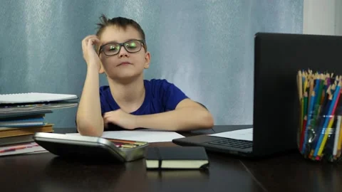 The boy listens to a remote lesson on the computer. he makes faces and laughs at Stock Footage 145145184