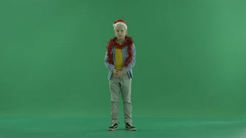 Boy is looking around in Santa hat, green chroma key background Stock Footage 86423385