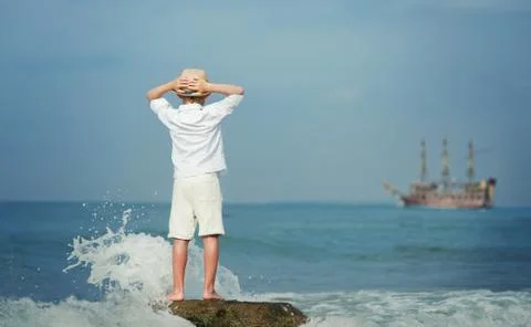 Boy looking on big old ship on the sea Stock Photos