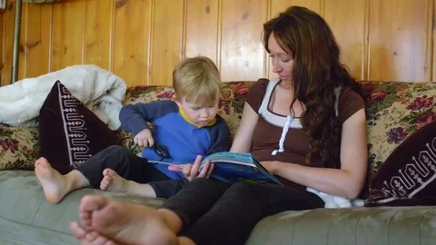 Boy looking in book with mother Stock Footage 80621461