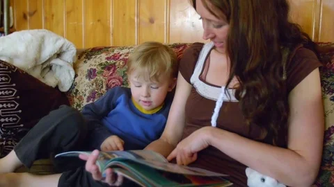 Boy looking in book with mother Stock Footage 80621538
