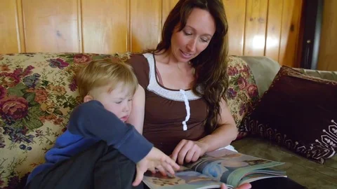 Boy looking in book with mother Stock Footage 80621579