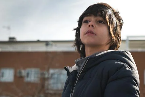 Boy looking up with contemplative expression in urban setting 스톡 사진