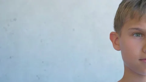 Boy looking directly to camera and smiling. Half face. Child near grunge gray Stock Footage 136232174