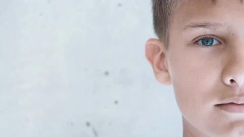 Boy looking directly to camera. Half face. Child near grunge gray wall Stock Footage 131914159