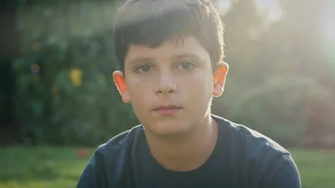Boy looking directly into the camera outdoors at sunset Stock Footage 275284960
