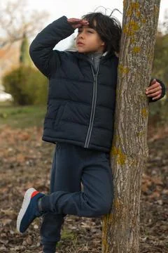 Boy looking into distance against tree in nature park Stock Photos