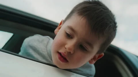 Boy looking down with his head sticking out of the car through the window, the Stock Footage 237058890