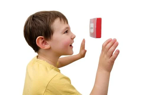 Boy looking at fire alarm button on wall. Curious child reaching out to touch Stock Photos