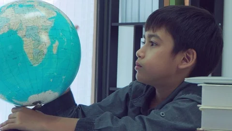Boy looking at globe and finding for a country on map Stock Footage 105631577