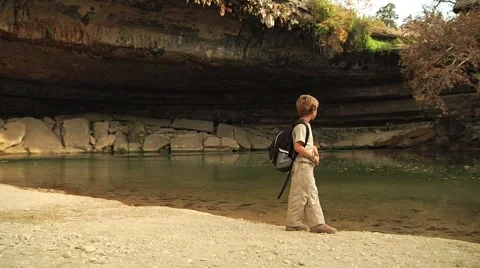 Boy looking at a grotto and pond Stock Footage 57360897