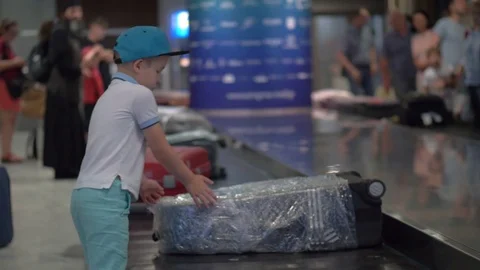 Boy looking for his suitcase on baggage conveyor belt at the airport Stock Footage 85246505