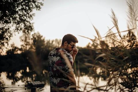 Boy looking interested in something through his sunglasses at sunset Stock Photos