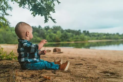 Boy looking out at the river on a beach Stock-Fotos