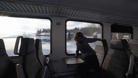 Boy looking out train window on winter scenic landscape Stock Footage 120980277