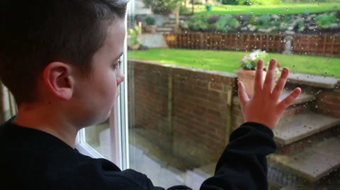 Boy looking out of window at miserable w... | Stock Video | Pond5