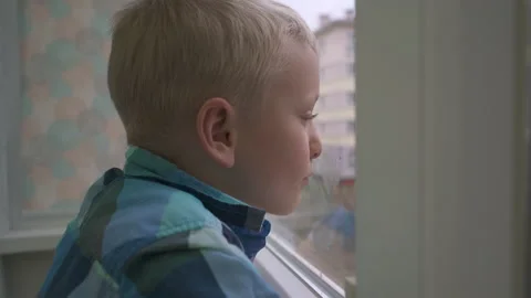Boy looking out the window waiting for parents at home alone Stock Footage 171290638