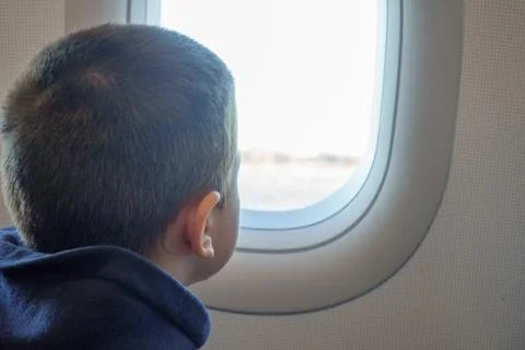 Boy looking outside of airplane window Stock Photos