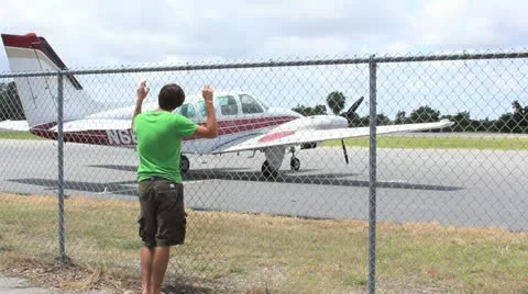 Boy looking at plane through fence Stock Footage 11427299