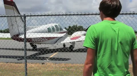 Boy looking at plane through fence Stock Footage 11427307