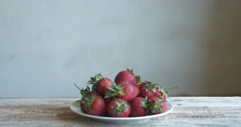 The boy is looking at a plate of strawberries Stock Footage 90853845