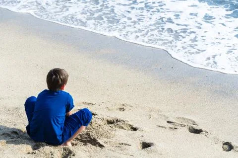 A boy looking at the sea with his back to the camera. Stock Photos
