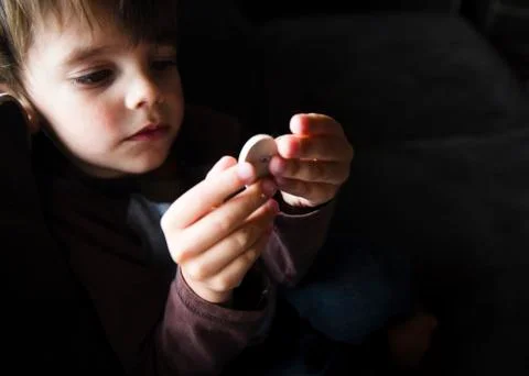 A boy looking at a small round button. 写真素材