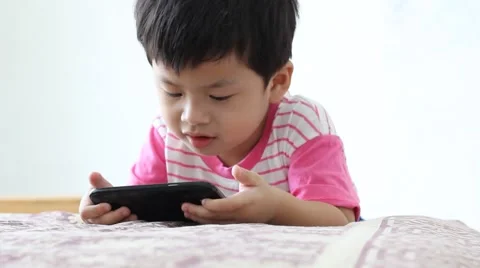 Boy looking at a smart phone with good intentions. 스톡 동영상 63500358